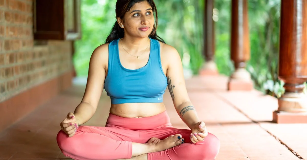 Jeune femme en posture de yoga méditant sur un tapis en plein air dans un cadre serein.