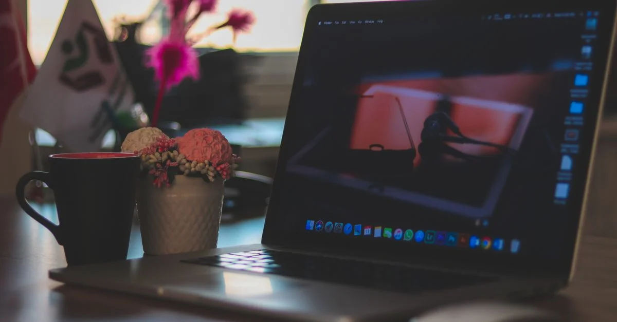Un espace de travail moderne avec un ordinateur portable, une tasse de café et des éléments décoratifs sur un bureau, idéal pour les environnements de travail à distance.