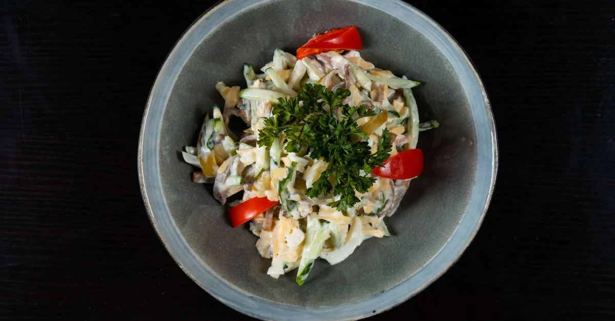 Délicieuse salade de légumes frais garnie de persil, servie dans un bol en céramique.
